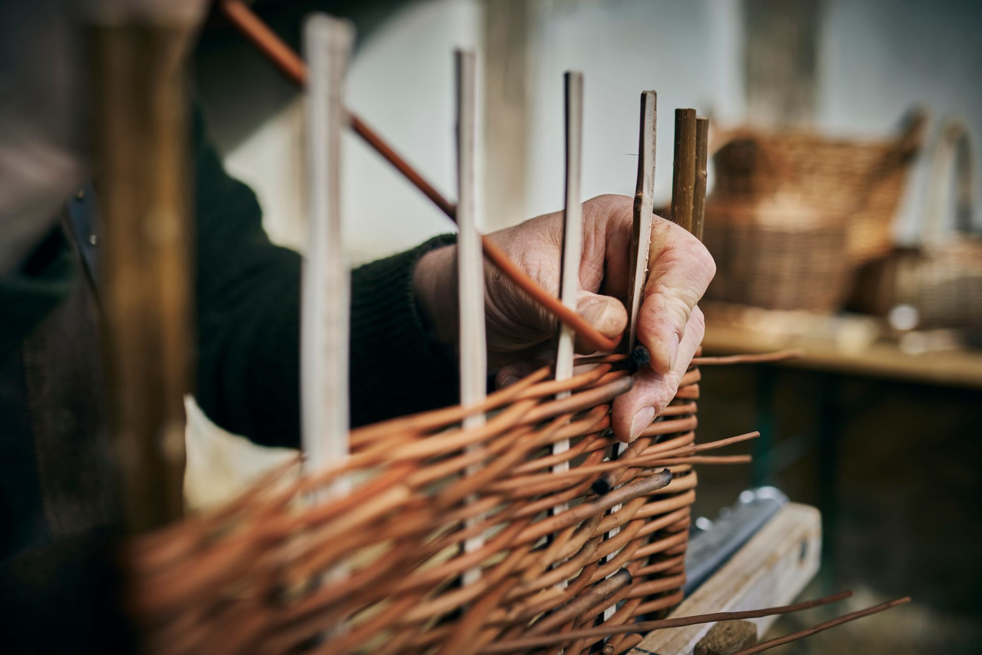 Close-up of basket maker weaving a basket in his workshop. Close-up of basket maker weaving a basket in his workshop.
