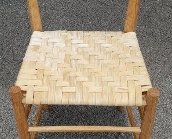 Wooden chair with a woven seat made of light-colored material.