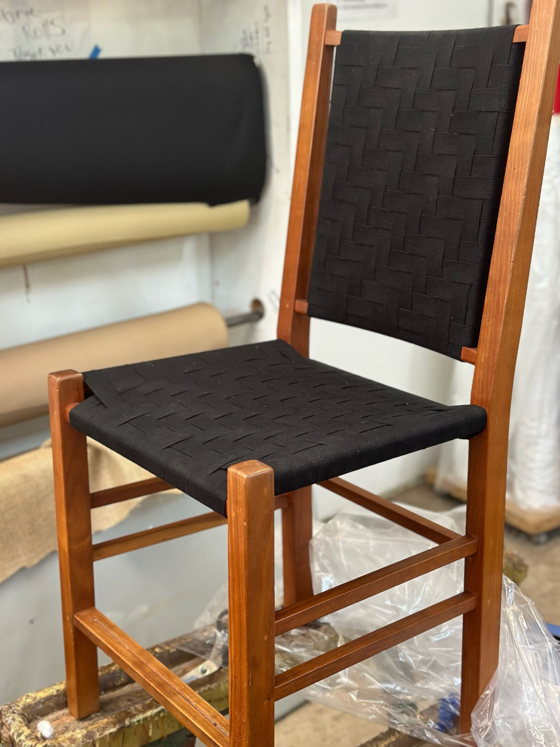 Wooden chair with woven black seat and back.