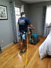 Technician cleaning a bedroom carpet with a blue and yellow carpet extractor