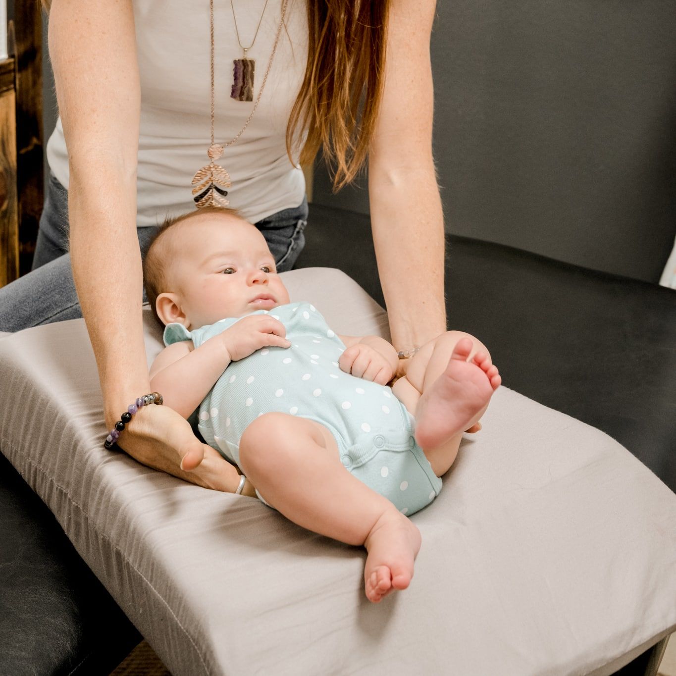 A woman is changing a baby 's diaper on a changing table