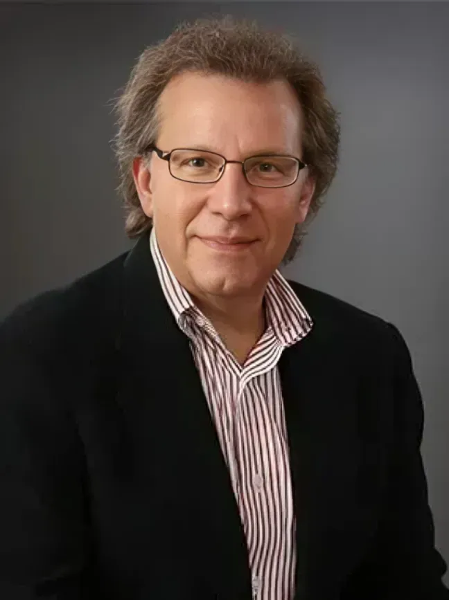 A man with a beard is wearing a blue suit and a blue shirt.