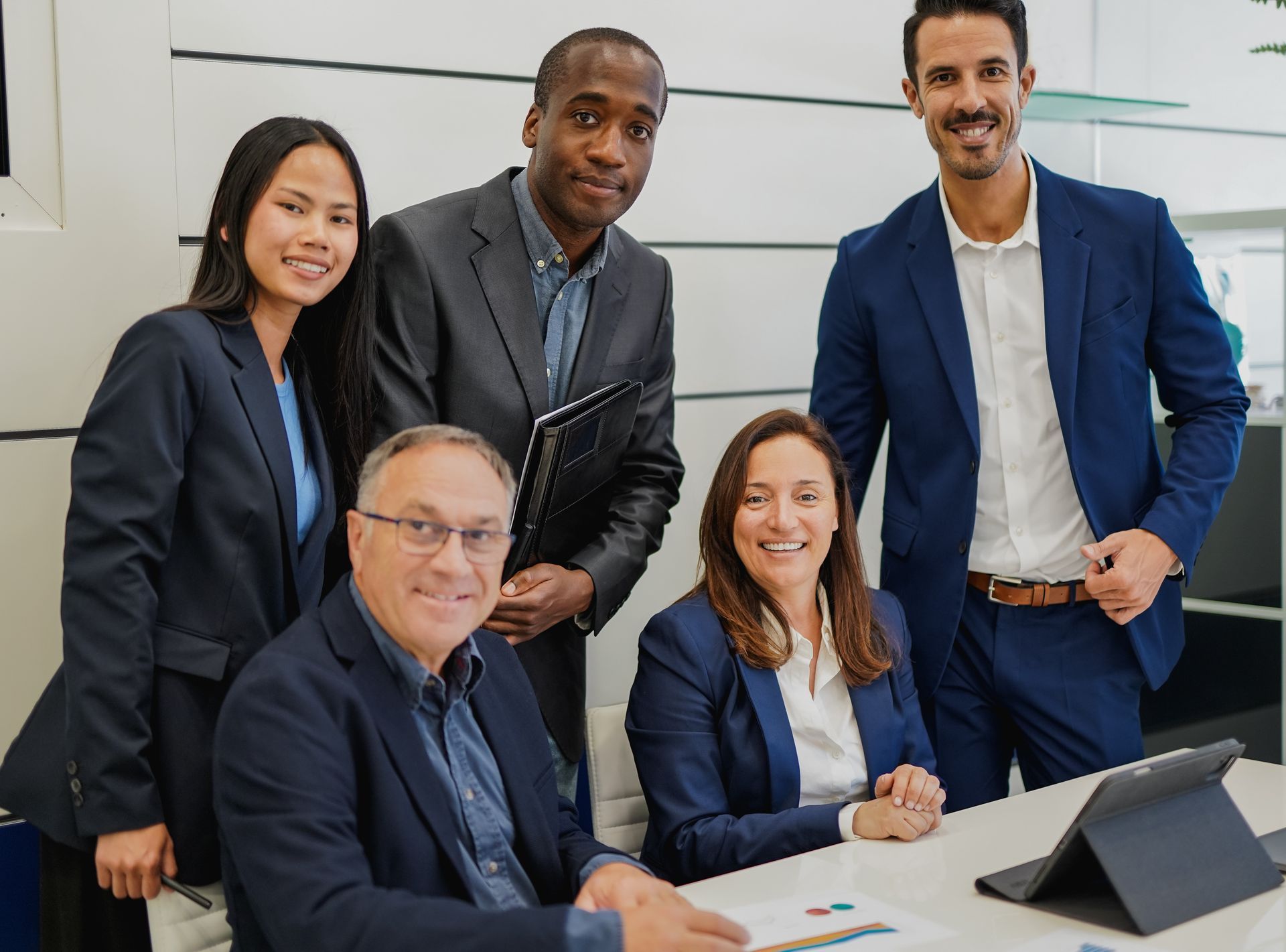 A diverse group of businesspeople smiling around a table in a modern office.