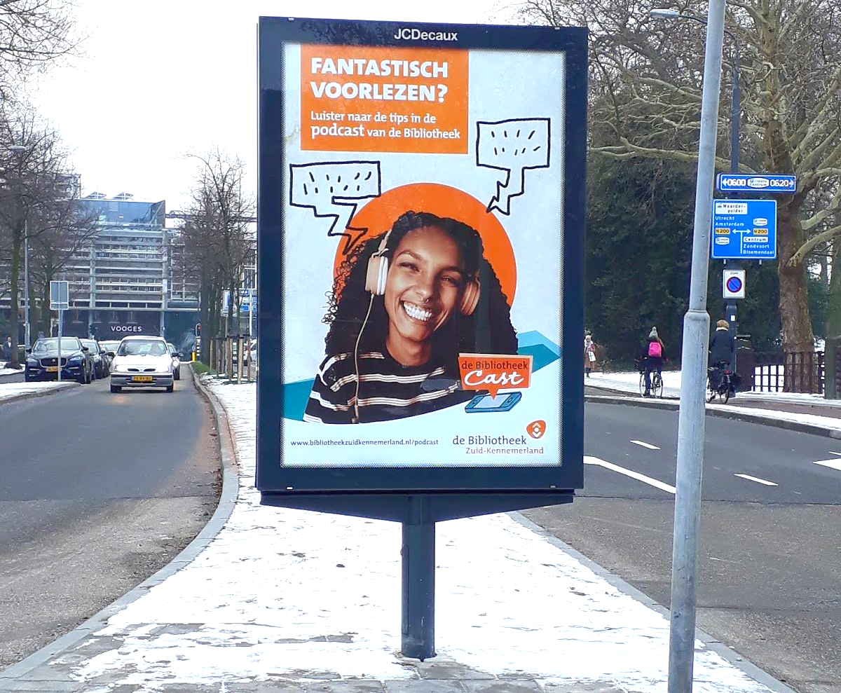 Reclamebord met een lachend persoon met koptelefoon, waarop
