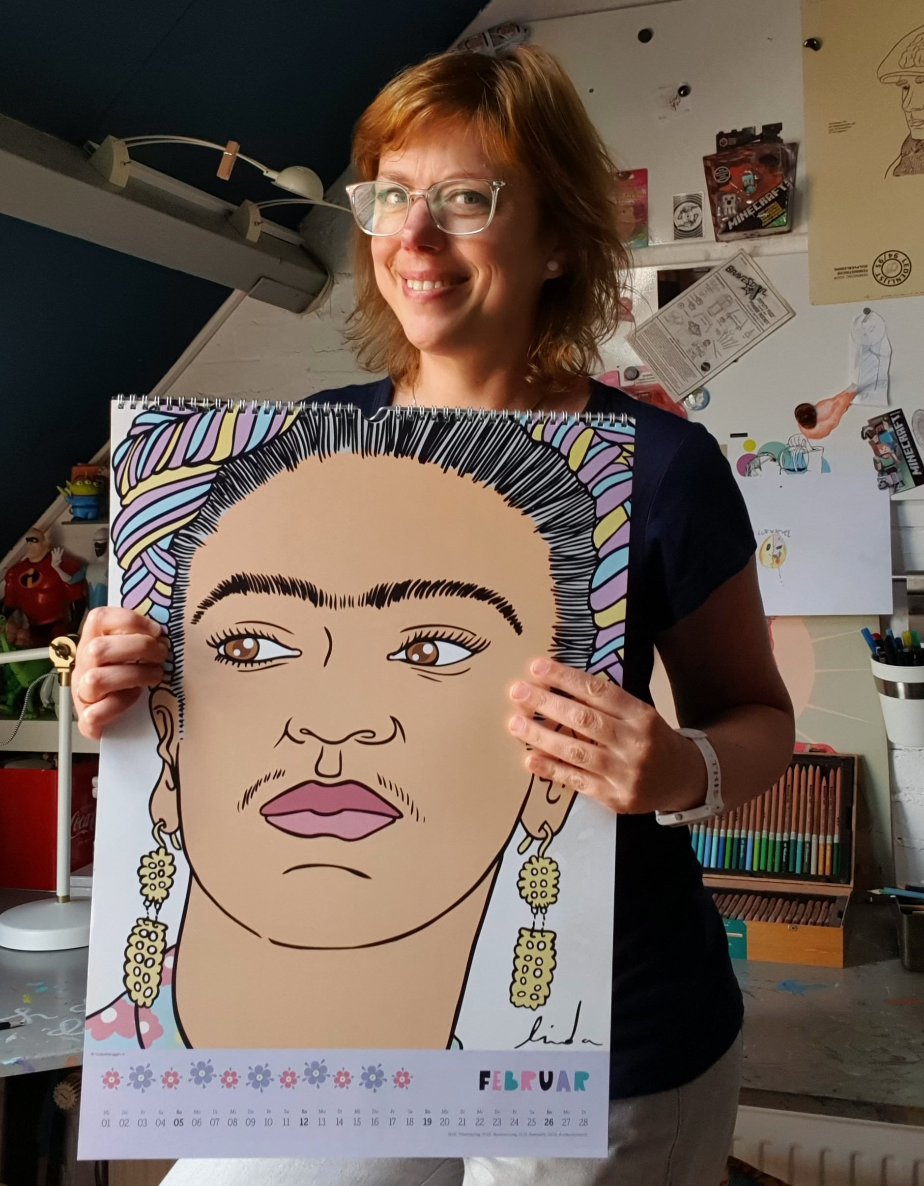 Vrouw met een kalender met een portret van Frida Kahlo in haar handen, lachend.