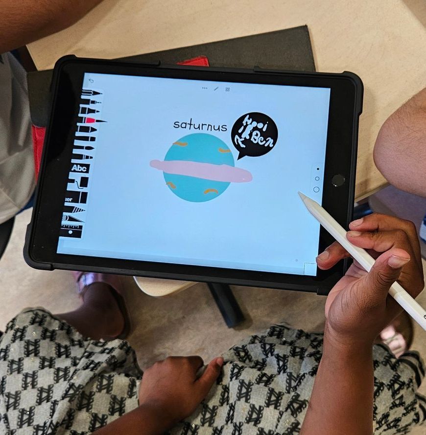 Een persoon tekent Saturnus op een tablet met een stylus. Het woord