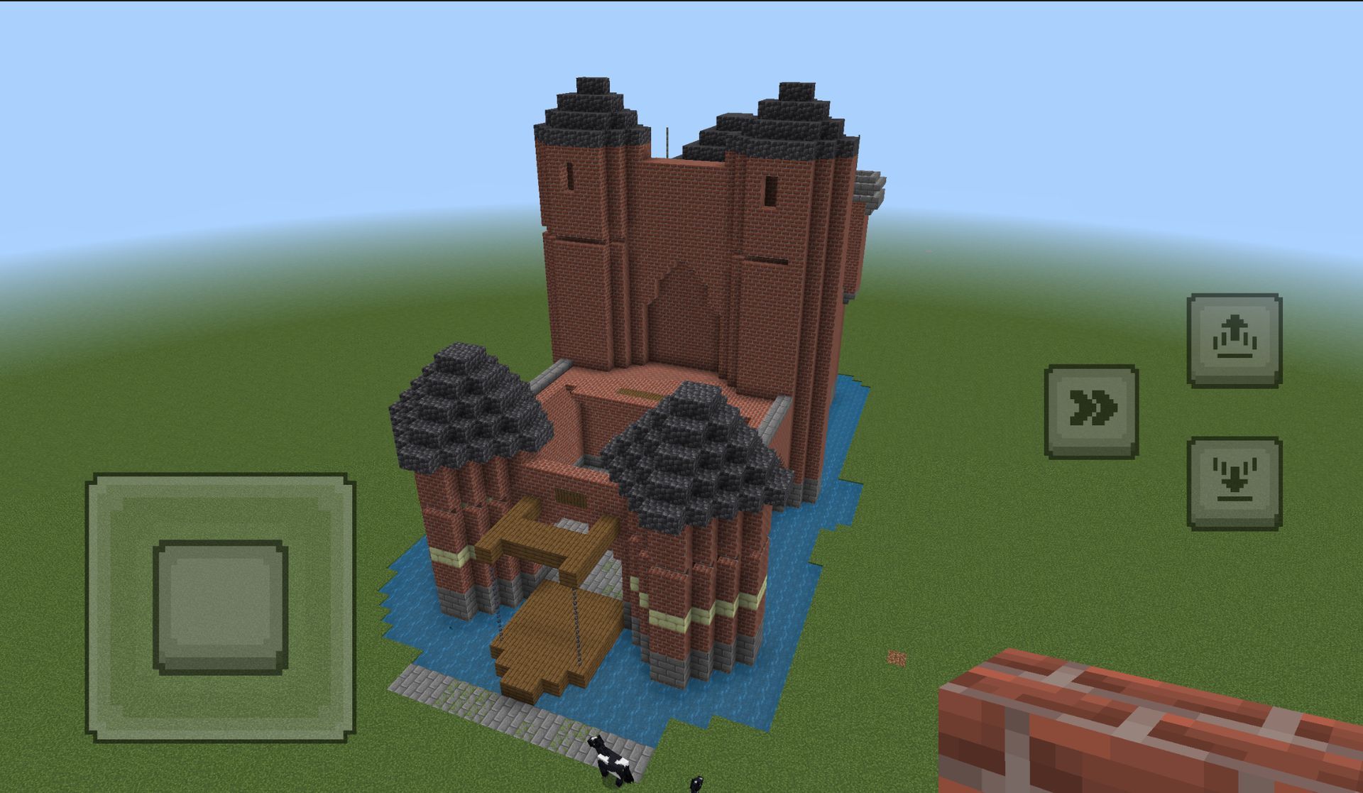Een Minecraft-kasteelstructuur van bakstenen, omgeven door water, op groen gras.