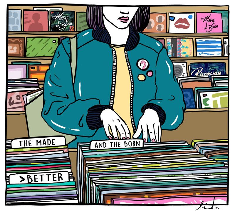 Vrouw die vinylplaten bekijkt in een platenzaak, gekleed in een turquoise jas.
