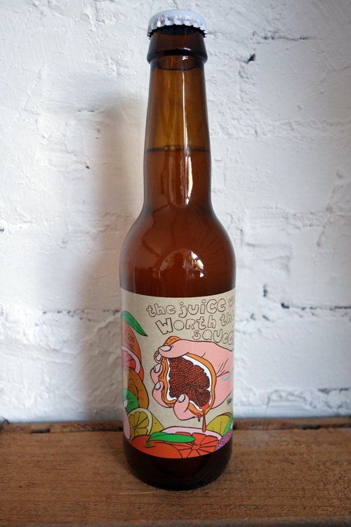 Bierfles met etiket waarop een cartoonillustratie staat van een sandwich die gegeten wordt, tegen een witte bakstenen muur.