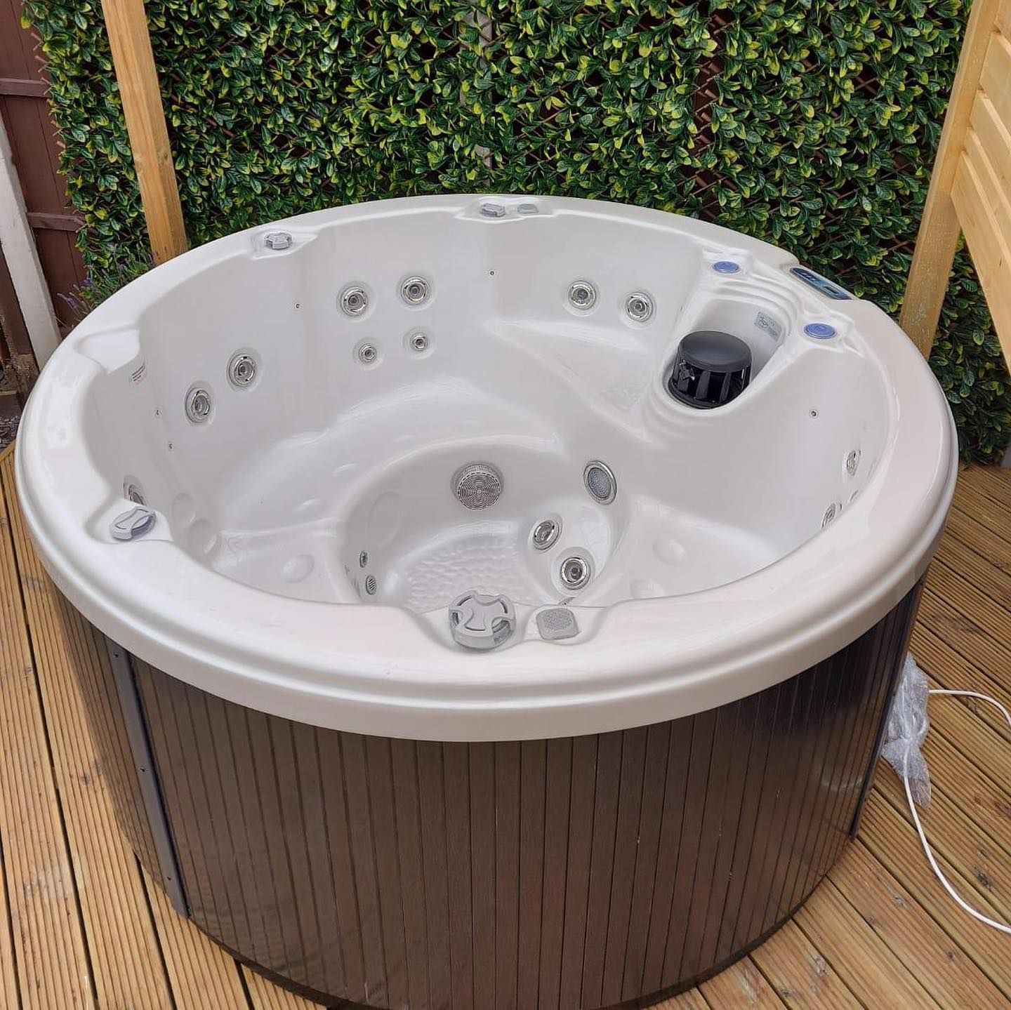 Round hot tub with beige interior and brown exterior, on a wooden deck.