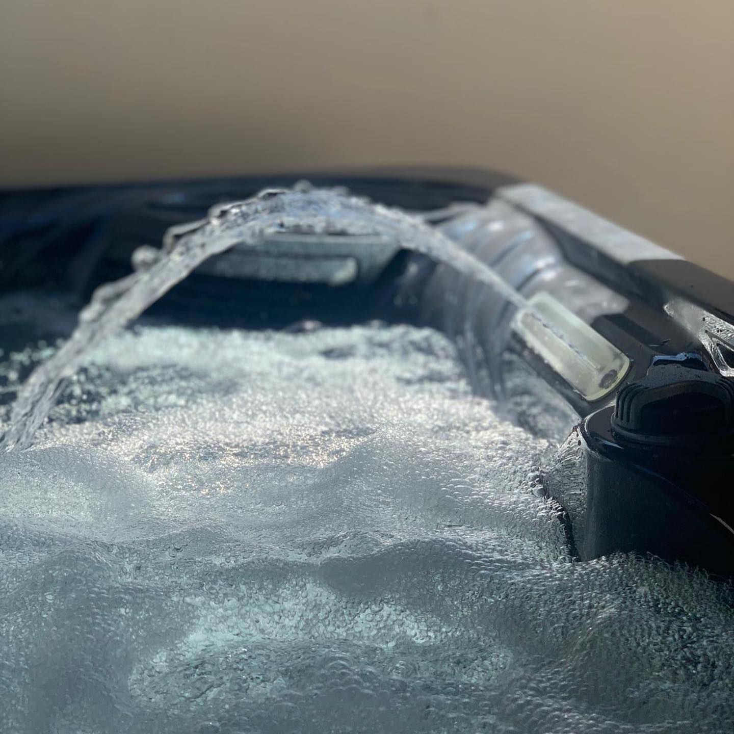 Bubbling water fountain in a hot tub, with foam and dark tub edges.