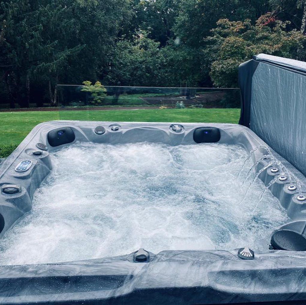 Bubbling hot tub on a grassy lawn with trees in the background.