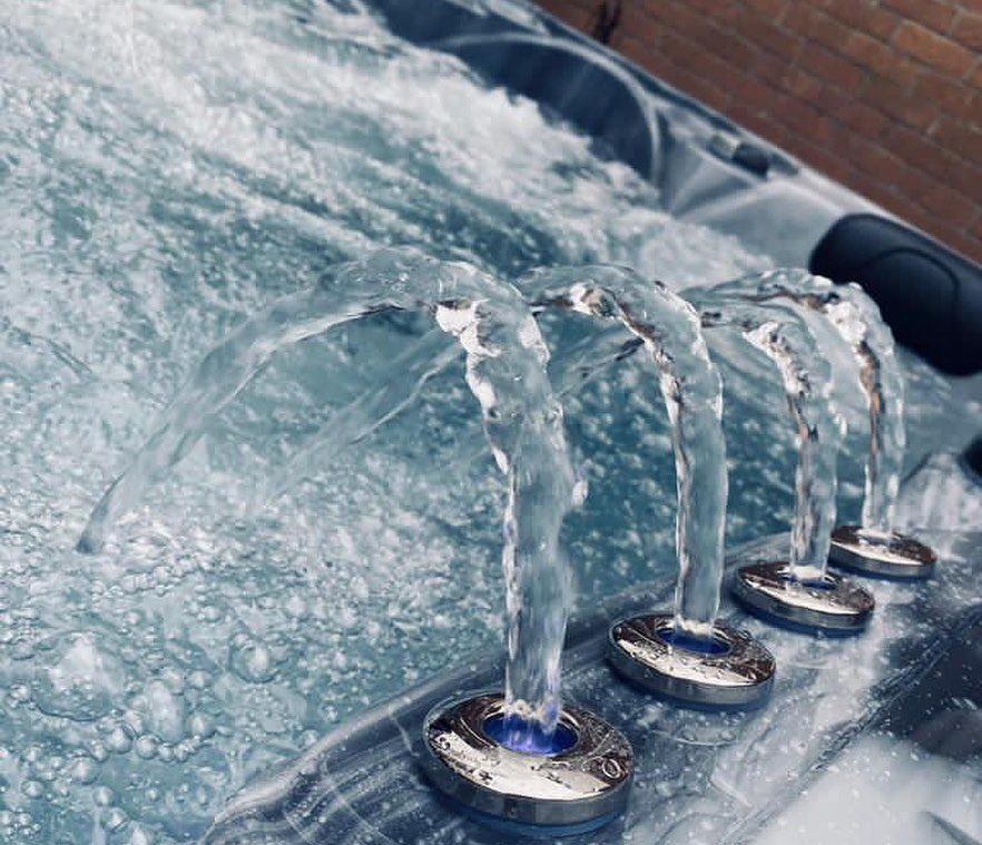Water jets shooting up from metallic fixtures in a bubbling hot tub.