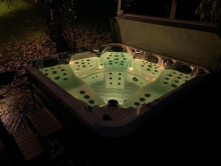 Lit hot tub at night, with green underwater lights.