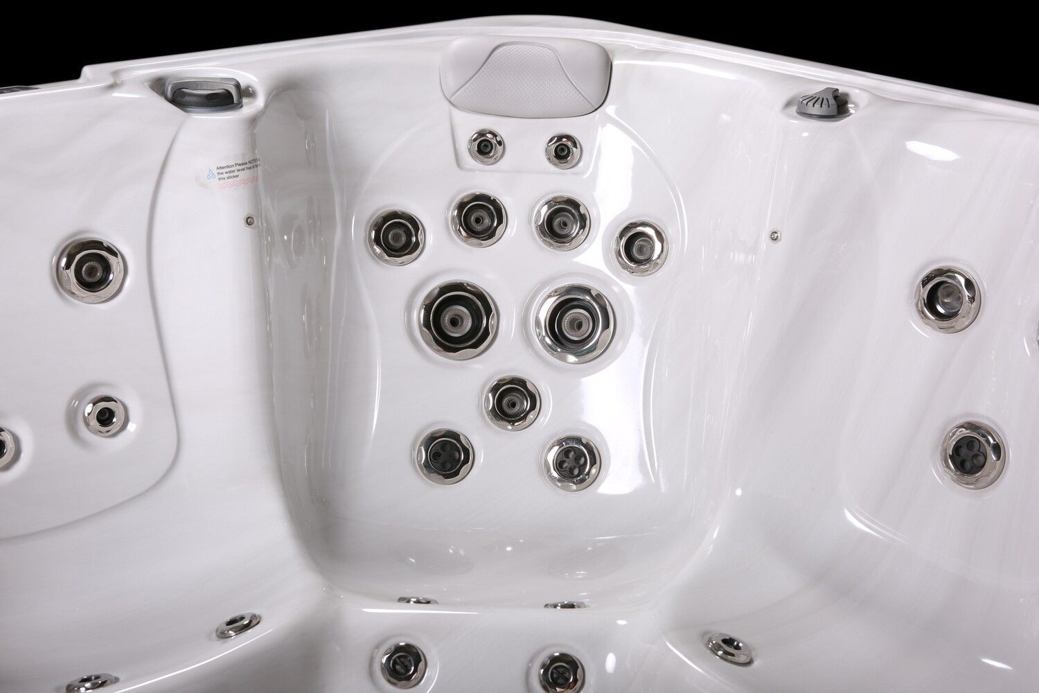 Close-up of a white hot tub interior with numerous jets and a control panel.