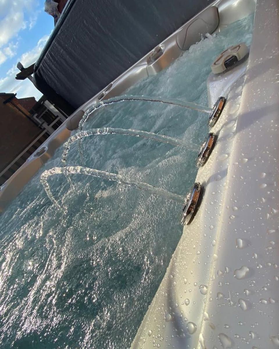 Jets of water spraying into a hot tub, outdoors under a blue sky.