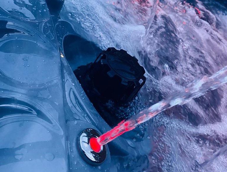 Water jets from a spa nozzle; focus on red and white button.