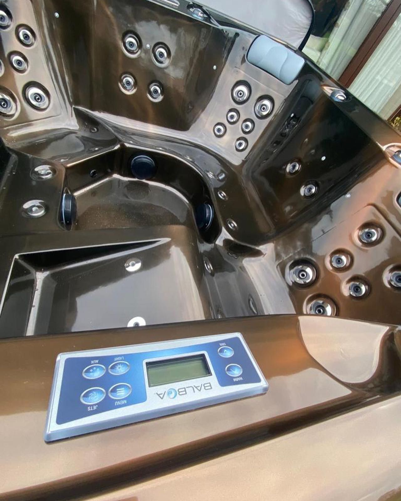 Dark brown hot tub interior with control panel and jets.