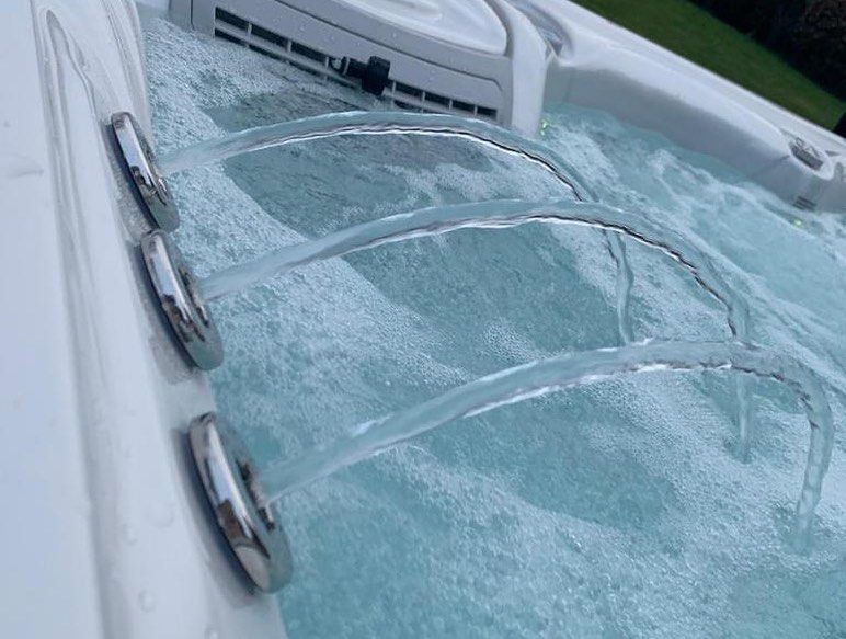 Hot tub with jets of water spraying into bubbly, blue water.
