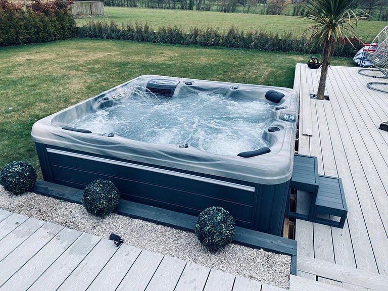 Hot tub on a wooden deck with a grassy yard in the background.