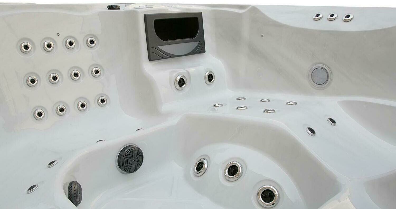 Grey hot tub interior with multiple water jets and control panel.