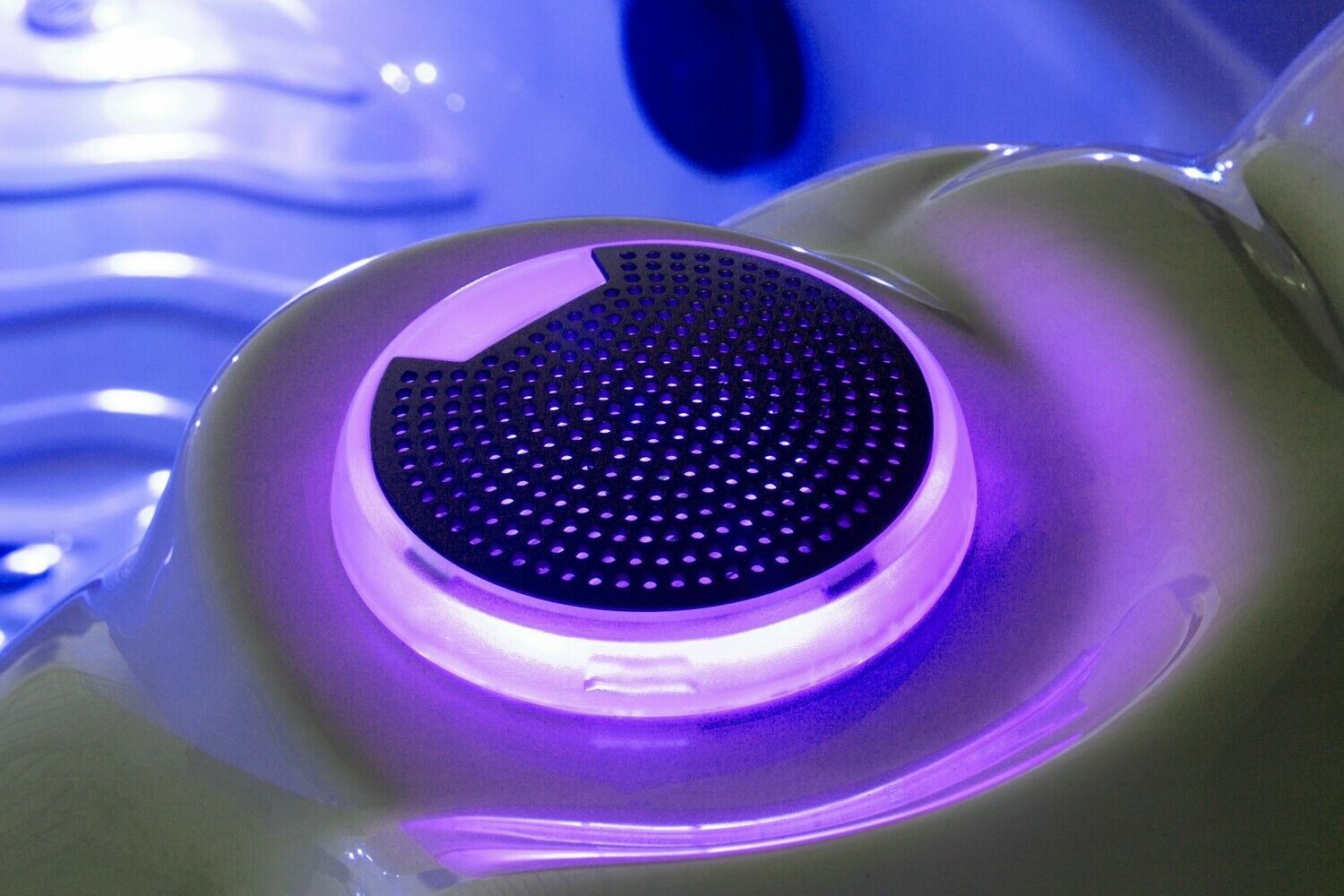 Purple-lit hot tub speaker, embedded in white curved surface.