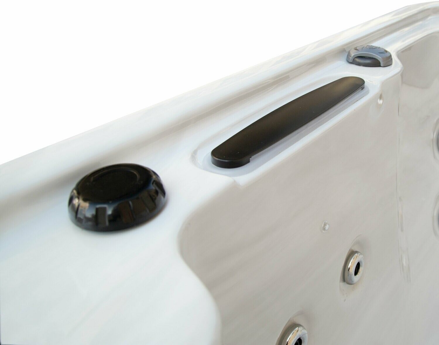 Close-up of a white hot tub rim with black control knobs and a handle, featuring jets.