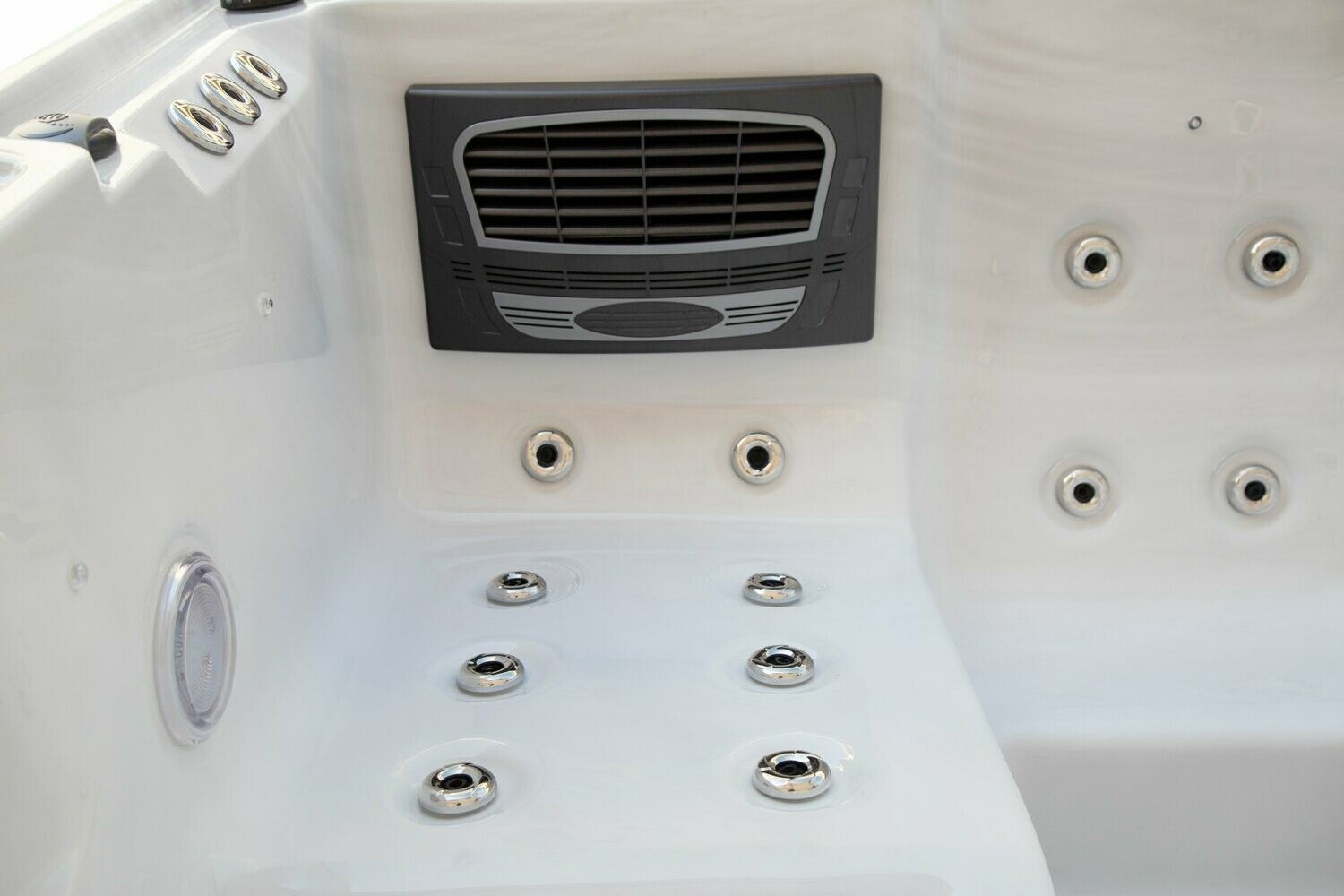 White hot tub interior with jets, vent, and control panel.