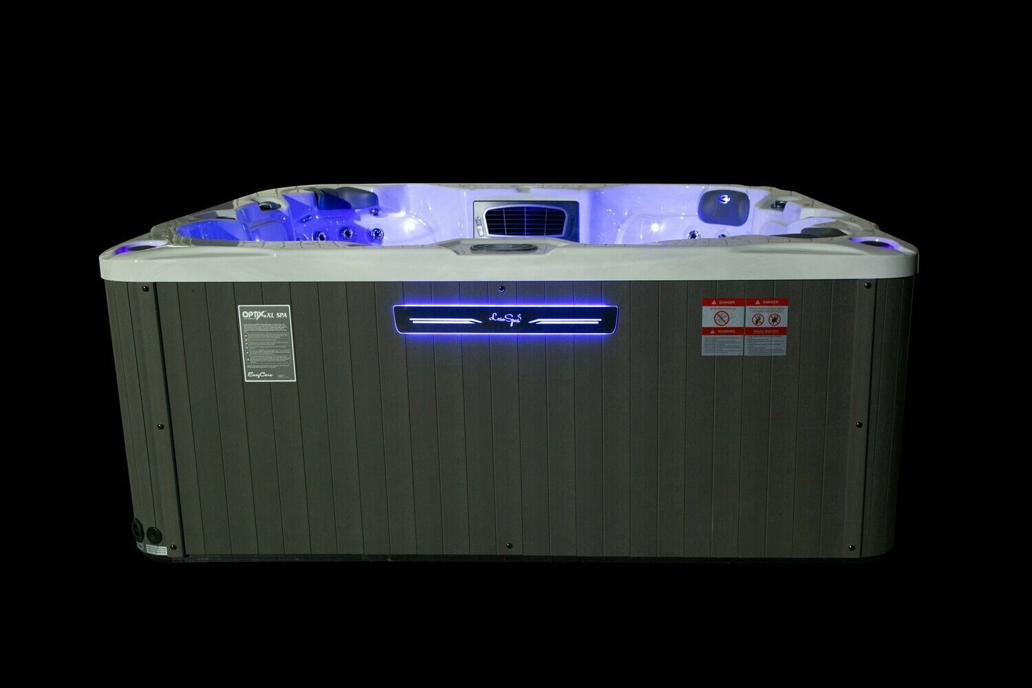 Hot tub with grey siding, lit blue inside and on a front panel, against a black background.