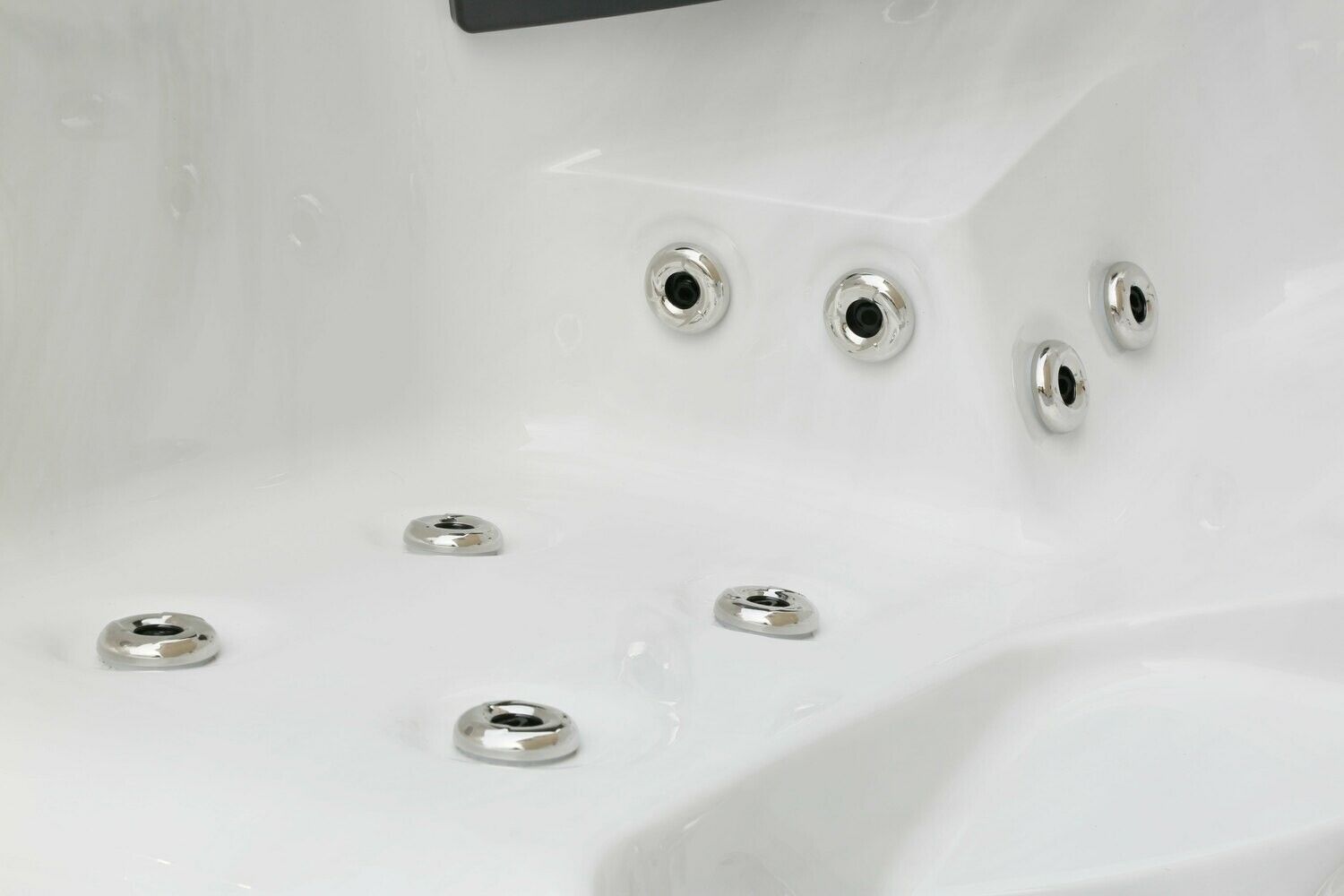 Close-up of a white hot tub interior, with several stainless steel jets installed in the surface.
