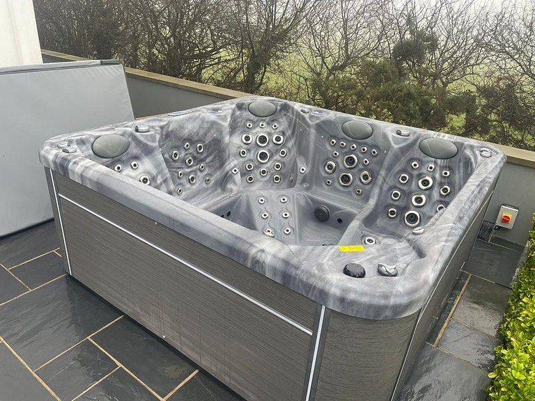 Hot tub, gray and marble-patterned interior, outdoors on a patio, with cover.