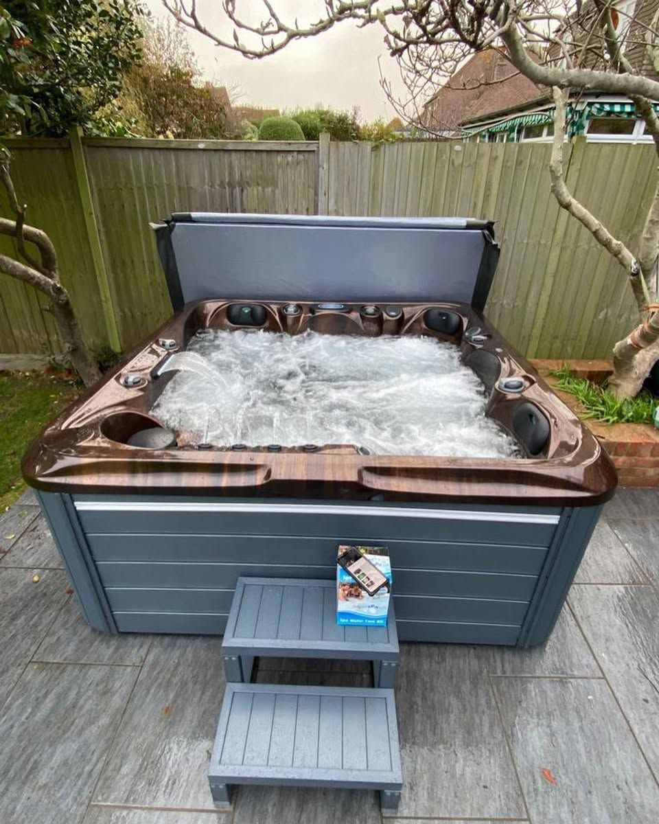Hot tub with cover open, set on a patio, with steps leading up to it.