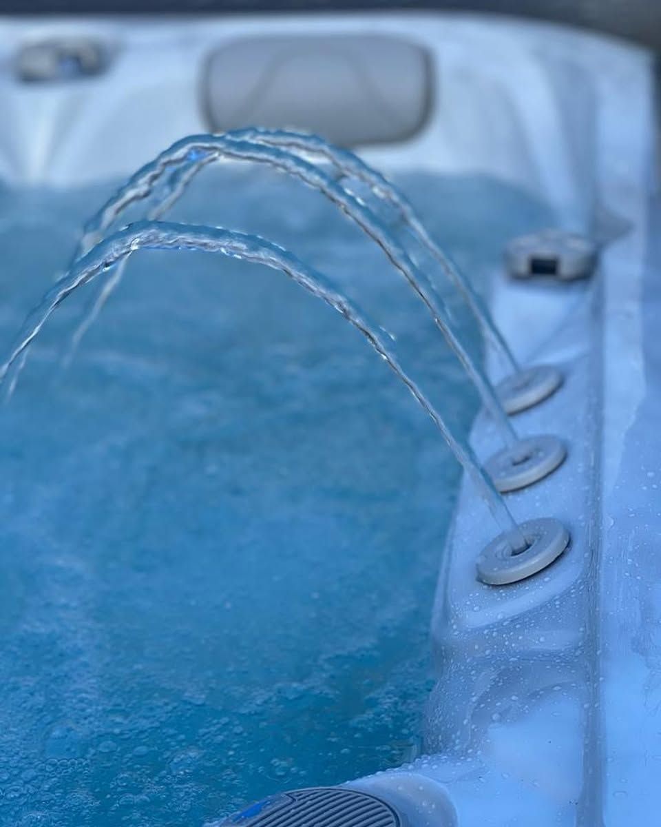 Close-up of a hot tub with three jets spraying water, creating arches.