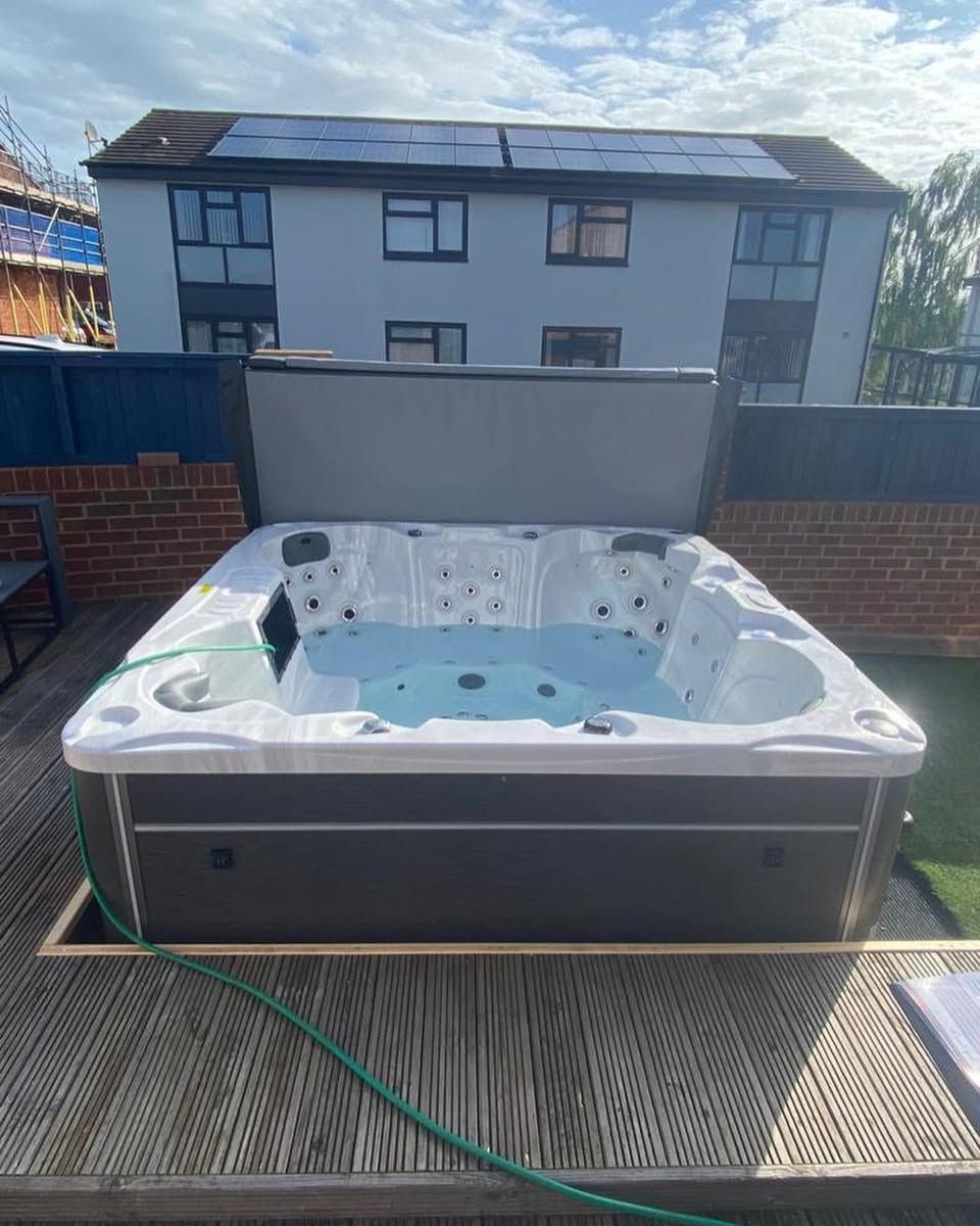 Hot tub on a wooden deck, against a house with solar panels.