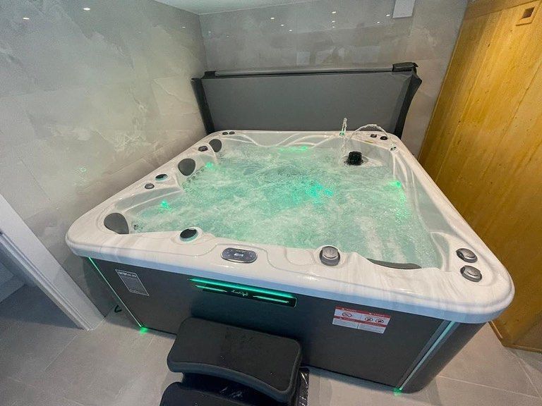 Triangular hot tub with bubbles and green lights, next to a door.