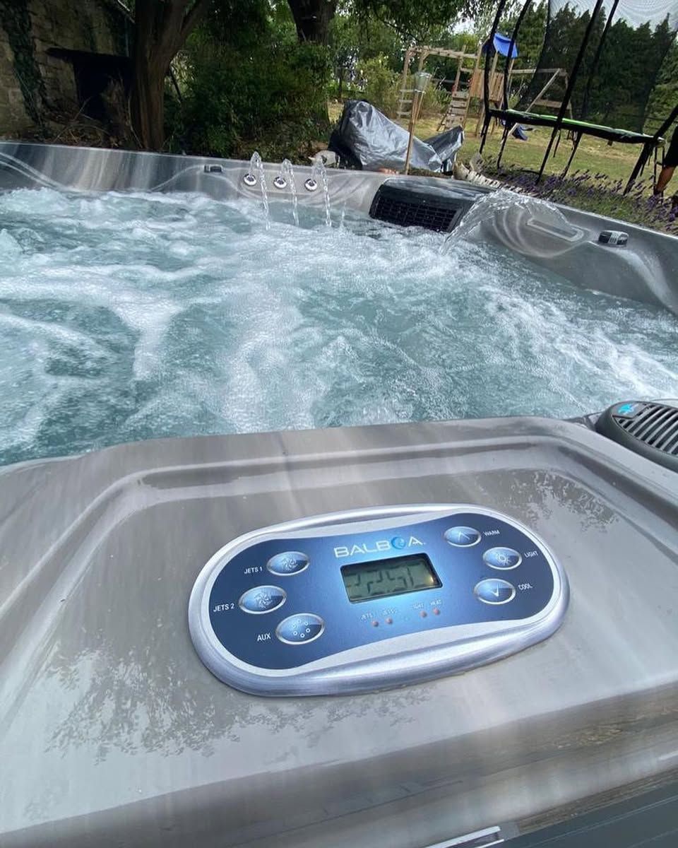 Bubbling hot tub with control panel, outside.