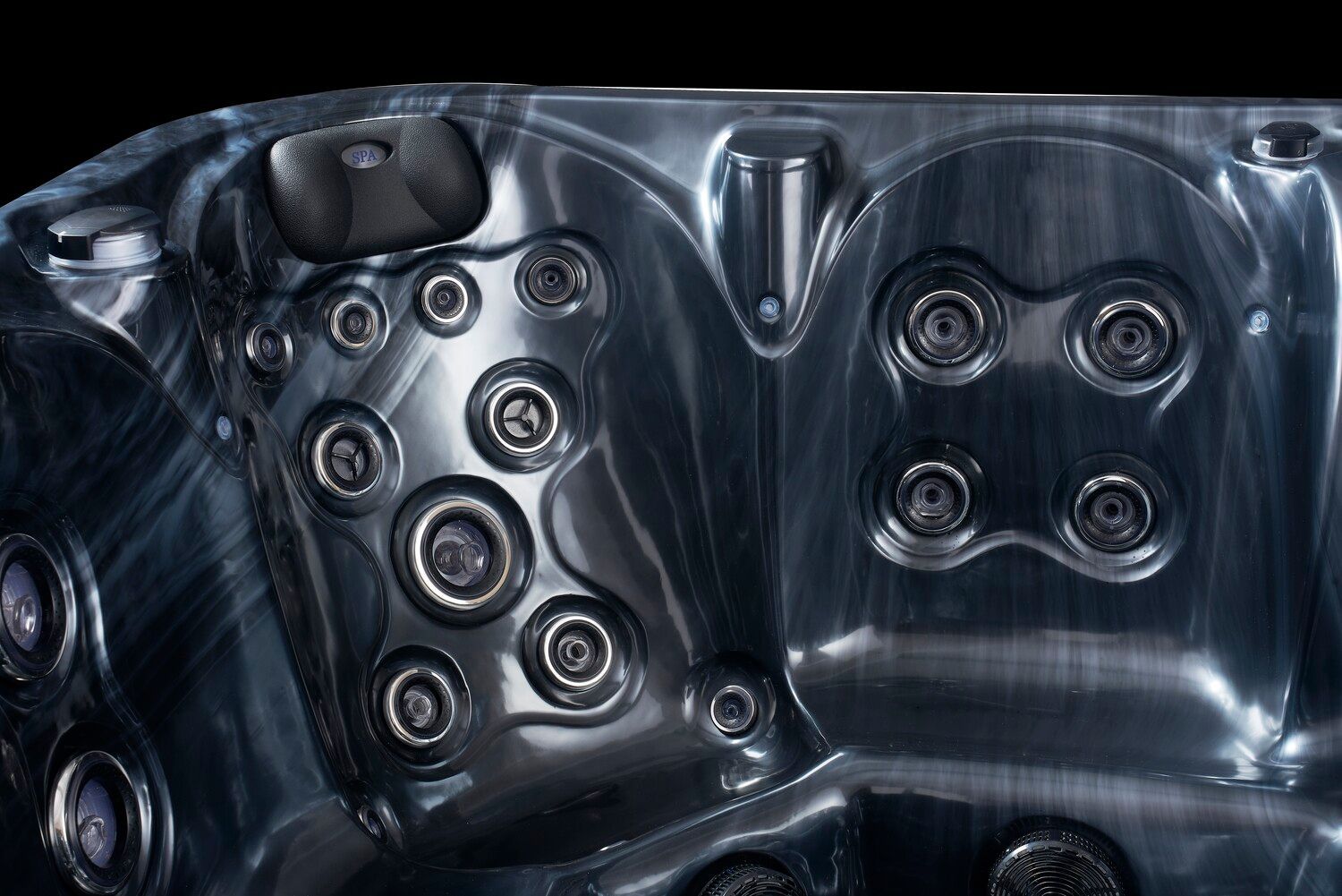 Close-up of a dark-colored hot tub interior with various jets and molded seating.