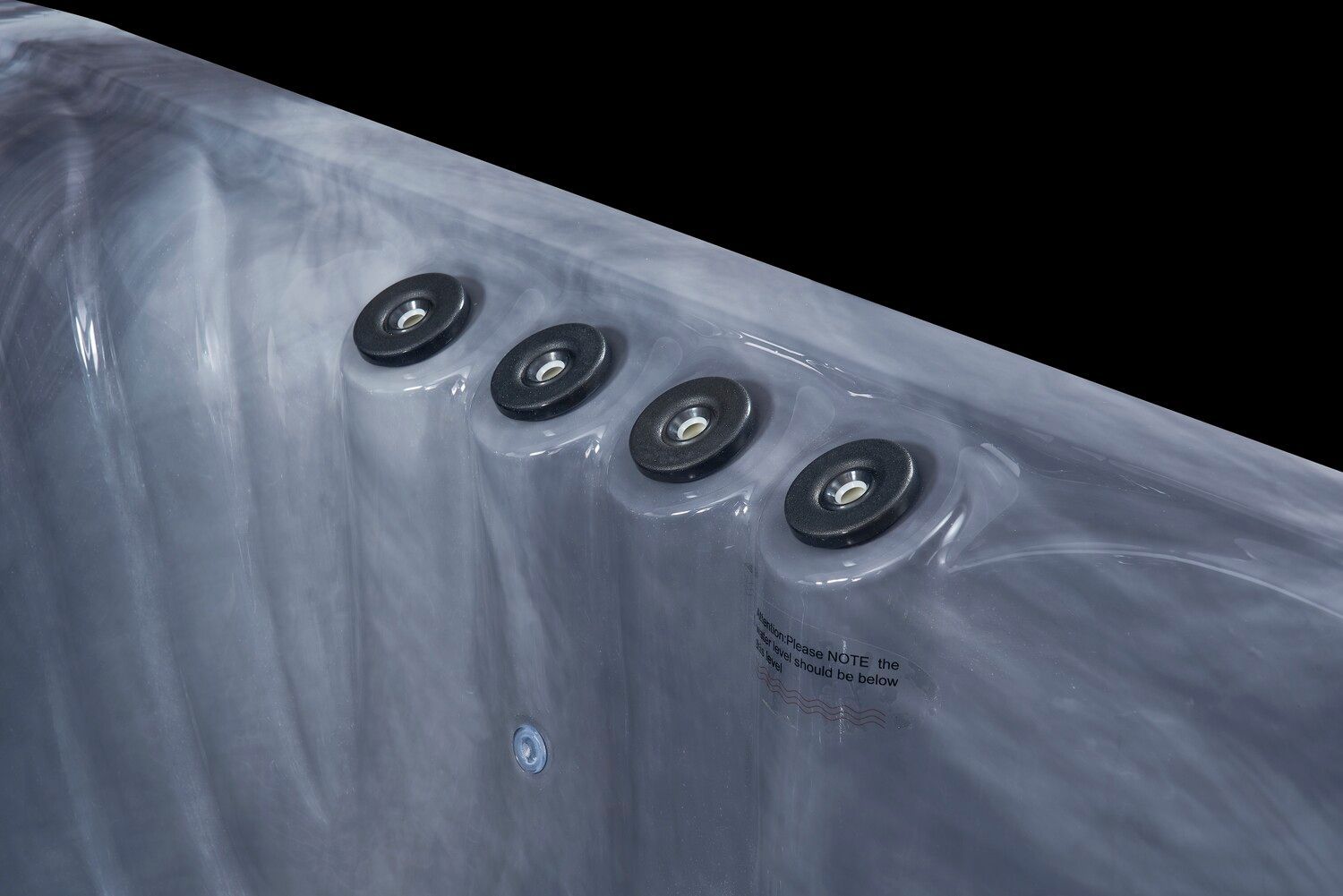 Four black jets with silver centers on the curved side of a gray hot tub.