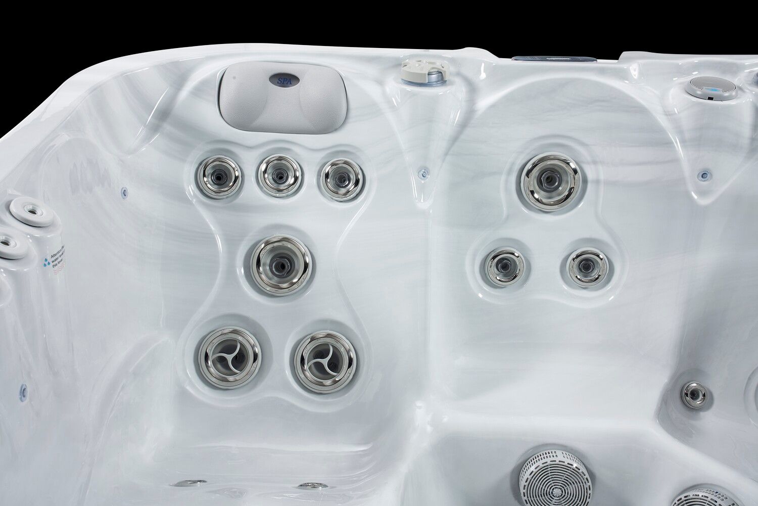 Close-up of a white hot tub interior with various water jets against a black background.