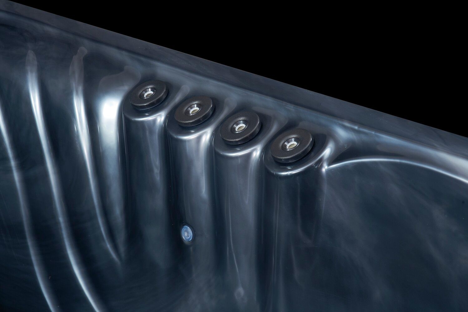 Four dark hot tub jets in a curved, reflective surface against a black backdrop.