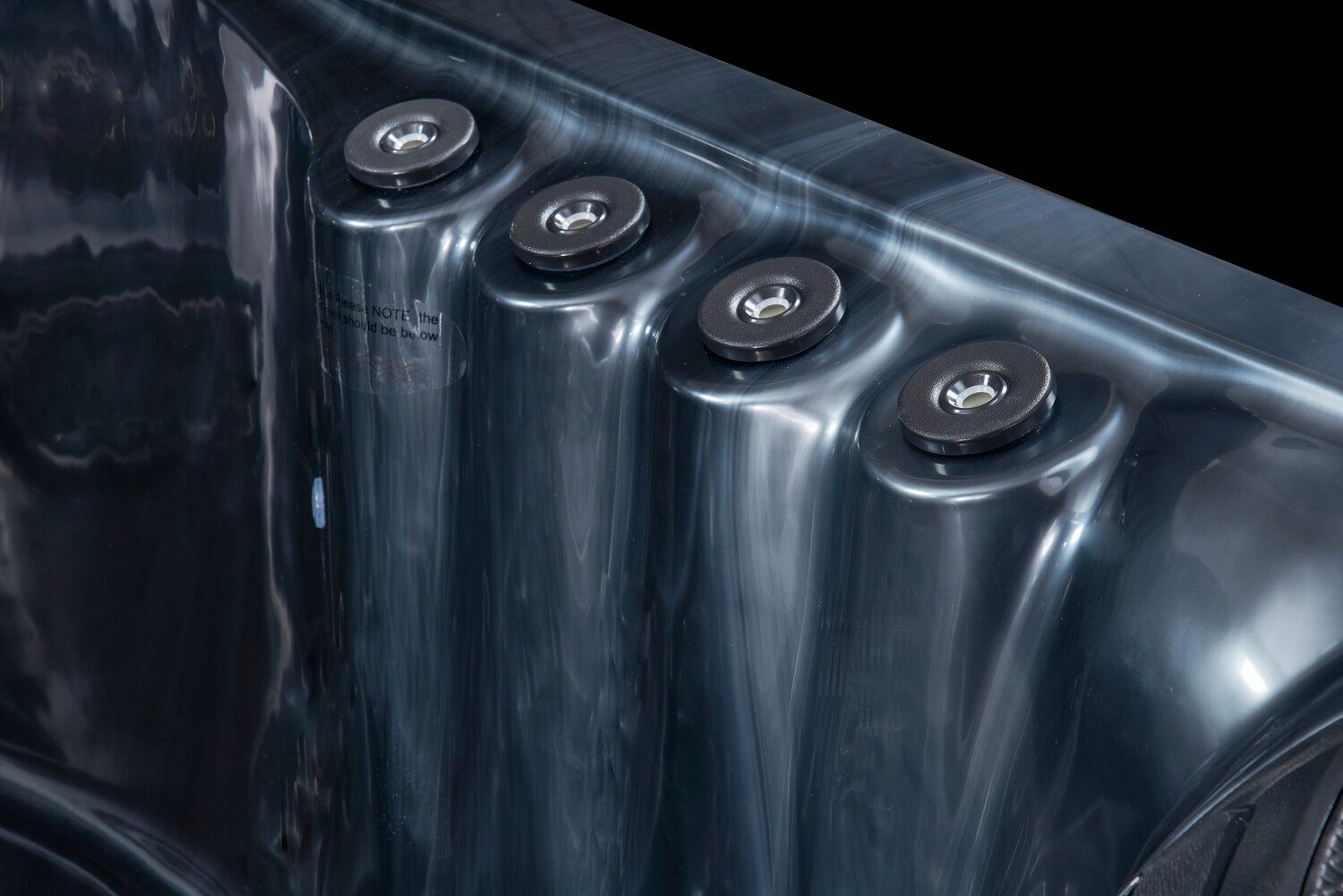 Close-up of a dark grey hot tub interior, showing four adjustable jets.