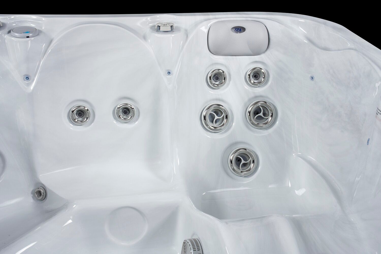 Close-up of a white hot tub interior with several water jets and control panel, black background.