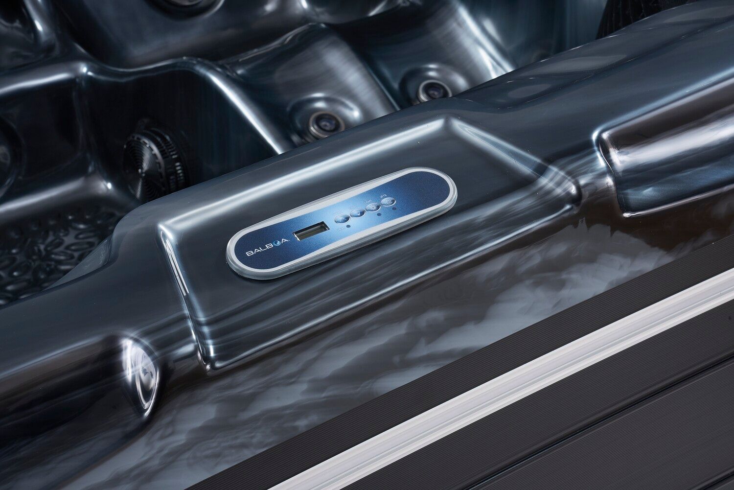 Hot tub control panel on the edge of a spa. Blue display, dark gray surround.