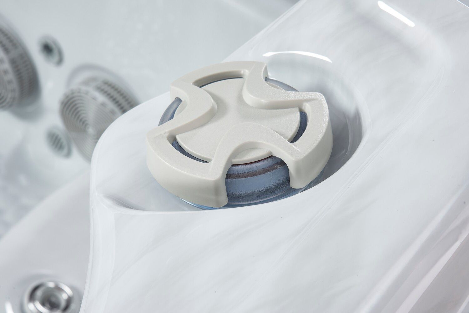 Close-up of a white hot tub jet control dial on a marbled white surface.