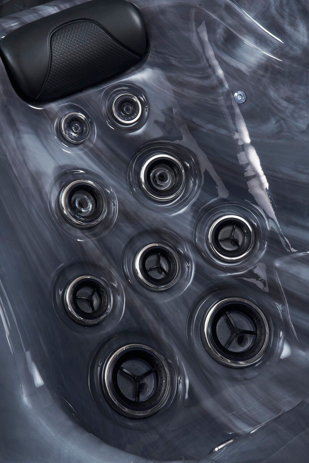 Close-up of a dark gray hot tub interior with various jets and a black headrest.