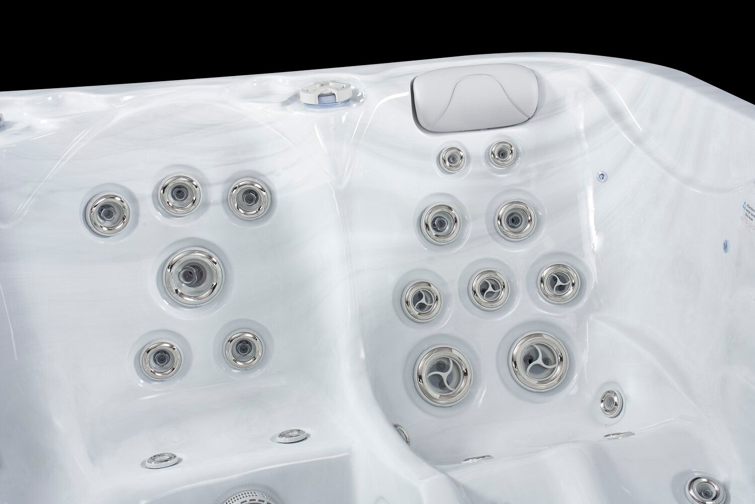 Close-up of a white hot tub interior with several jets. The tub has two seating areas and a headrest.