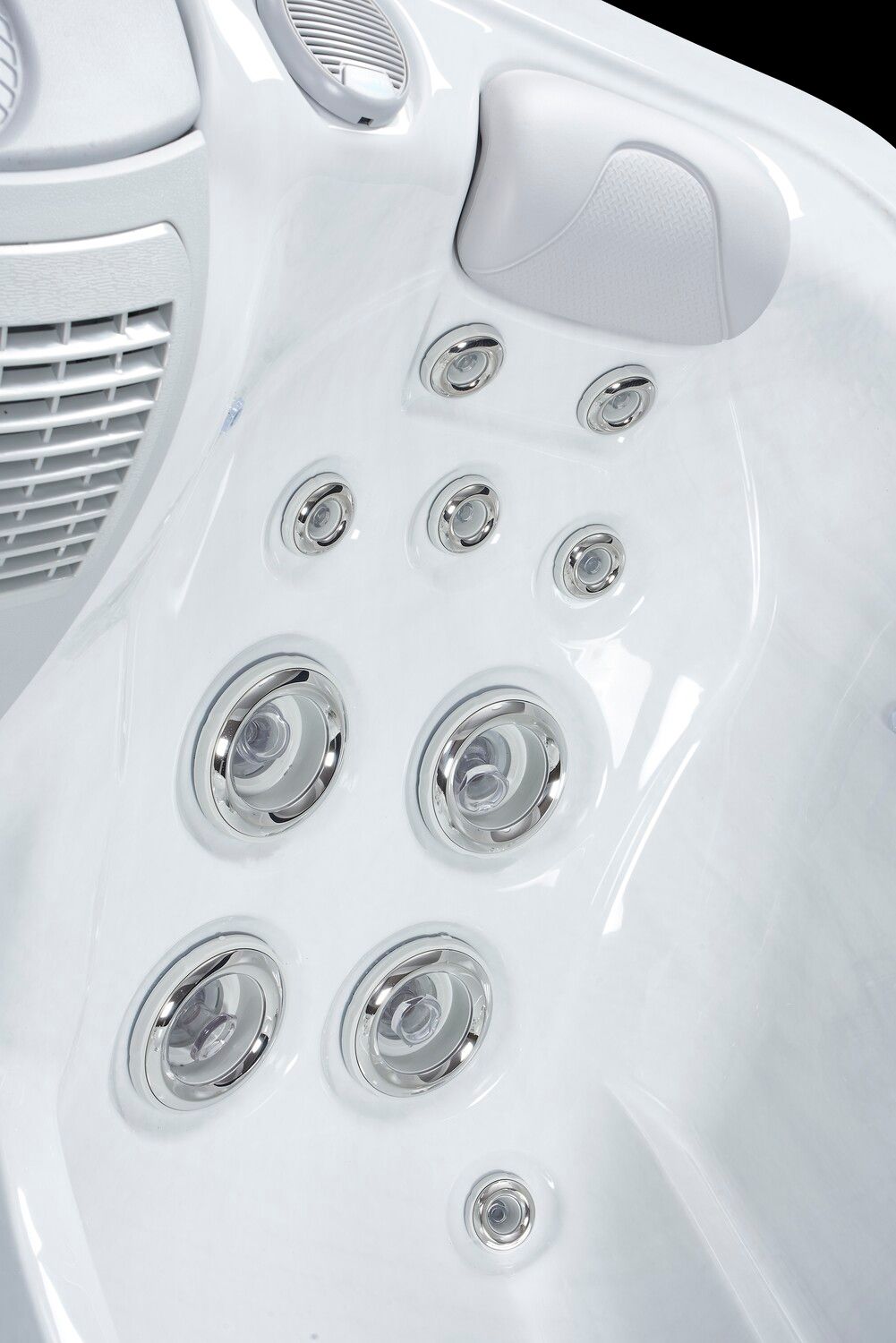 Close-up of a white hot tub interior, showing water jets, headrest, and ventilation.