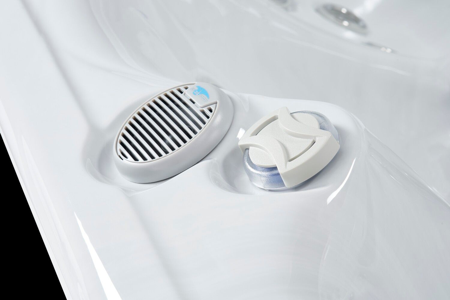 Two white spa accessories in a white tub: a speaker and a sanitizer dispenser.