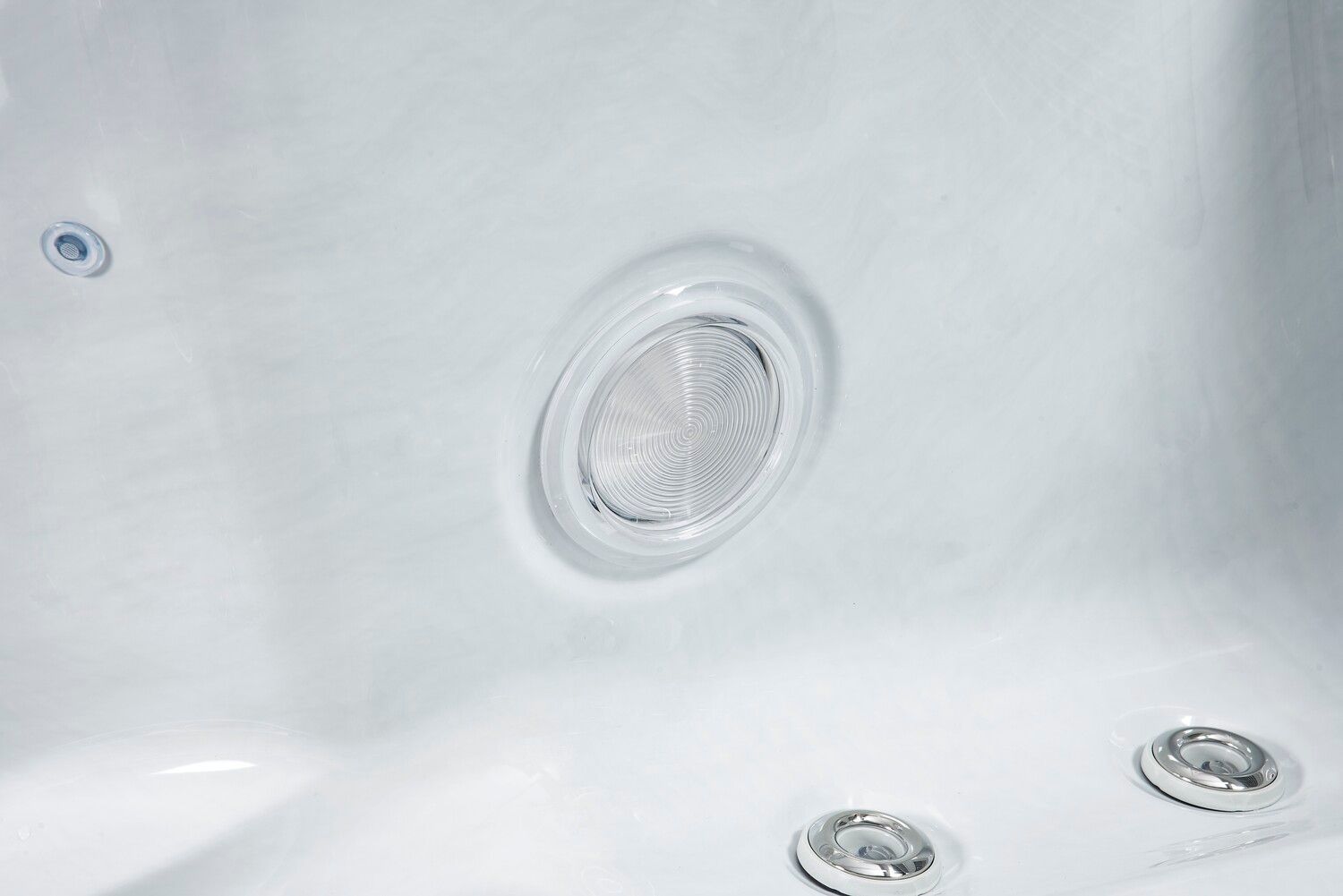 Close-up view of a white hot tub interior, showing water jets and a drain.