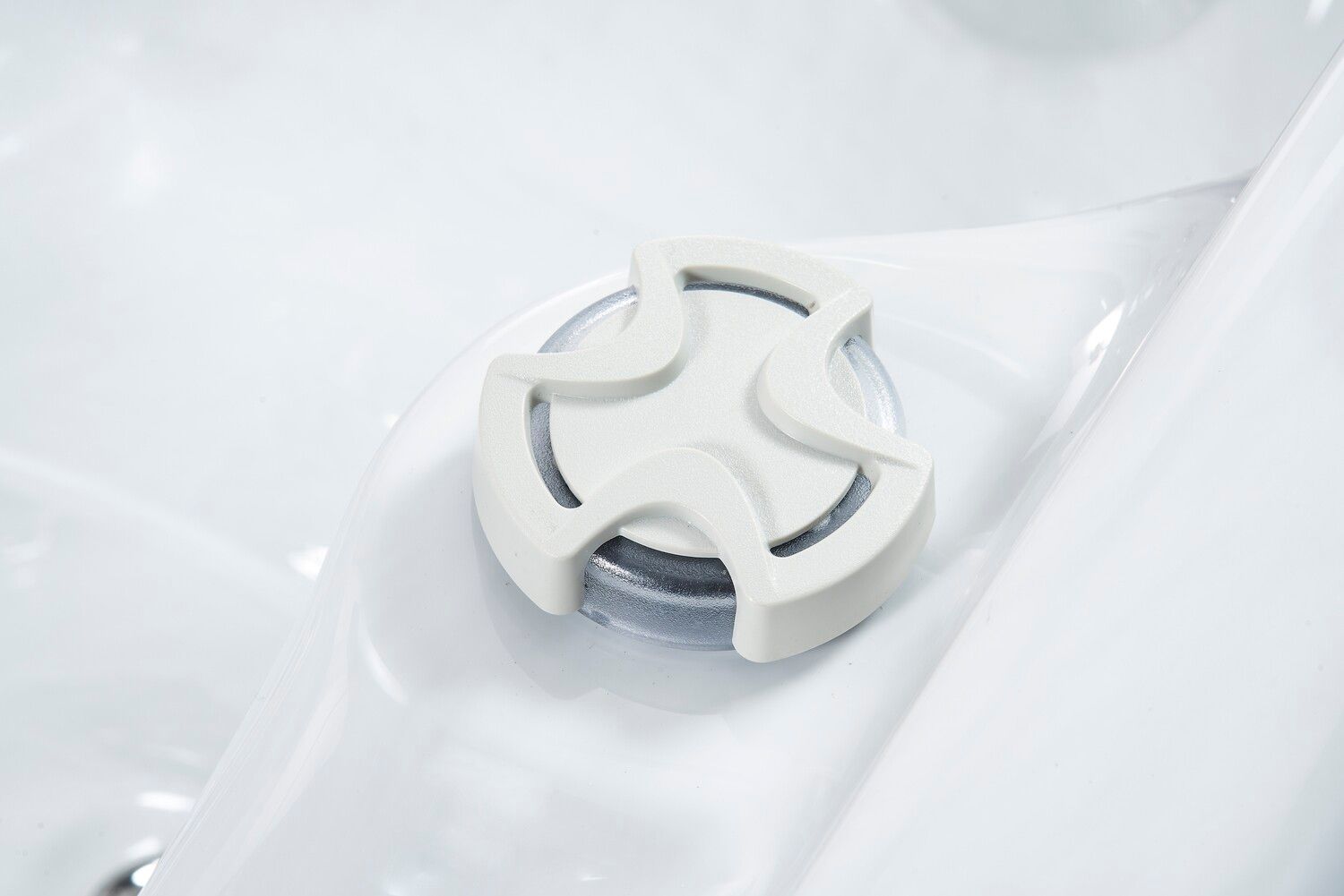 White hot tub jet with a star-shaped, adjustable nozzle, set in a white tub interior.